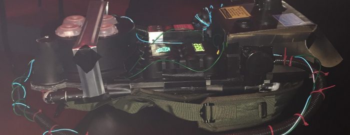 Ghostbuster Proton Pack laying flat on a table in a dark room